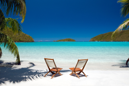 two teak chairs between palm trees at a perfect beach in the Virgin Islands